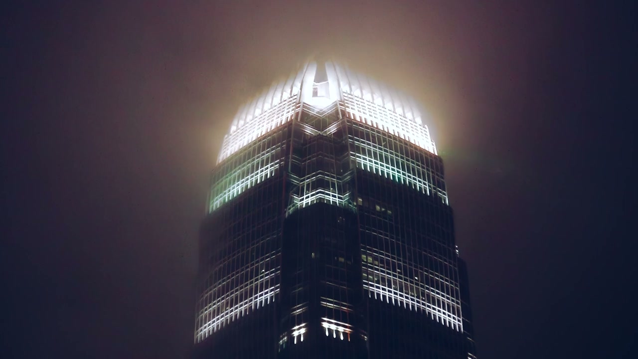 A skyscraper crowned with light at night